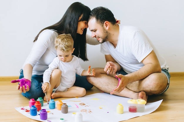 fils de famille heureux avec les parents qui peignent une affiche