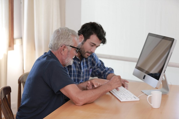 Le fils hipster adulte et le vieux père senior restent pour le travail à la maison deux générations ont une barbe qui parlent ensemble et se détendent avec le sourire heureux aiment vivre jusqu'à l'isolement en quarantaine à la maison la fête des pères