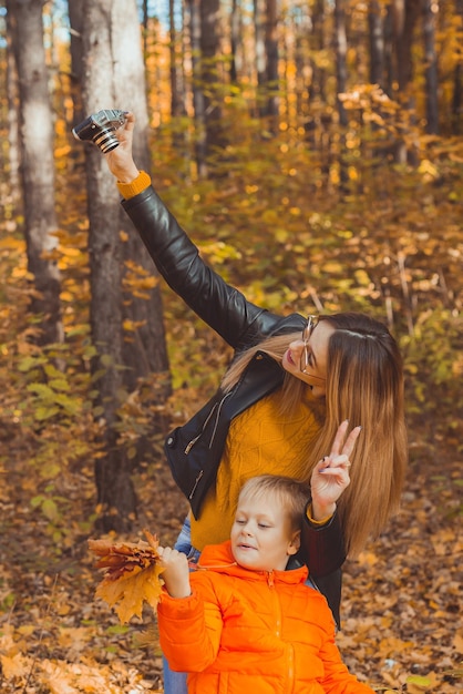 Fils et mère prennent selfie devant la caméra dans le parc d'automne loisirs monoparentaux et saison d'automne conc