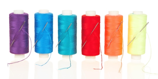 Fils multicolores sur bobines avec aiguilles isolés sur fond blanc