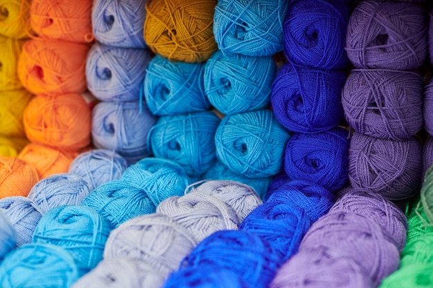 Fils ou pelotes de laine sur des étagères en magasin pour le tricot et la couture, gros plan. Accessoires pour la mercerie dans les étagères des magasins en tissu. Image multicolore, arrière-plan.