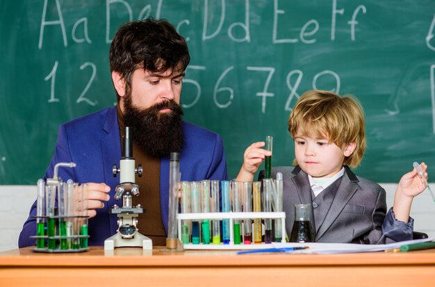 Fils et père à l'école petit garçon avec enseignant homme salle de formation avec tableau noir Flacon dans la main scientifique avec des tubes à essai Sagesse Retour à l'école Imaginez la grandeur