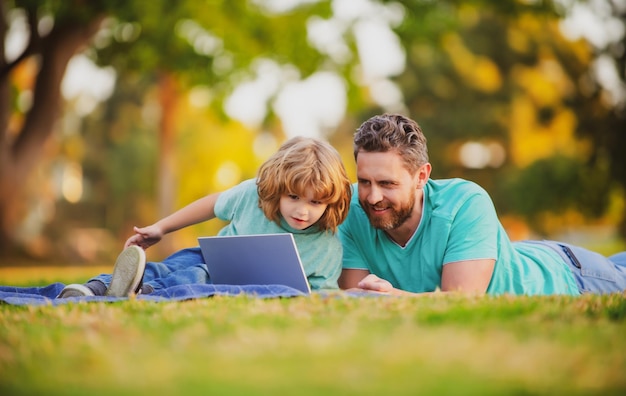 Fils avec père regardant la leçon sur un ordinateur portable à l'extérieur