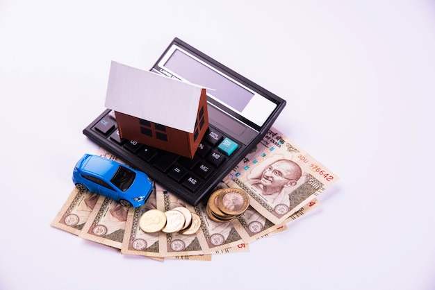 Financement automobile et prêt ou achat de logement en Inde - Concept montrant un modèle de voiture et de maison en 3D, des clés, des billets de banque indiens et une calculatrice, etc.