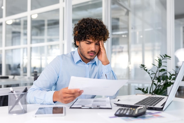 Un financier contrarié qui regarde le tableau des ventes et des revenus de l'homme d'affaires de l'entreprise à l'intérieur du bureau déçu