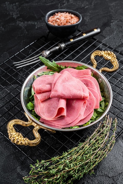 Fines tranches de jambon dans une poêle avec salade de roquette Fond noir Vue de dessus