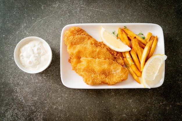 fish and chips - filet de poisson frit avec chips de pommes de terre et citron sur plaque blanche