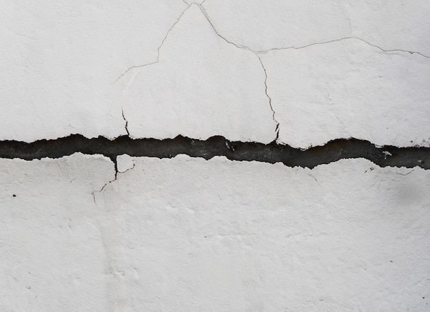 Une fissure dans un mur blanc avec une fissure dedans.