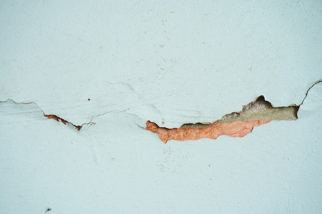 Fissure sur un mur de béton peint en bleu.