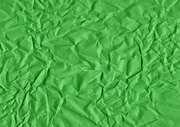 Fissures et déchirures sur une feuille de papier froissée verte