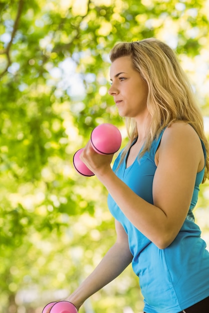 Fit blonde soulevant des haltères dans le parc