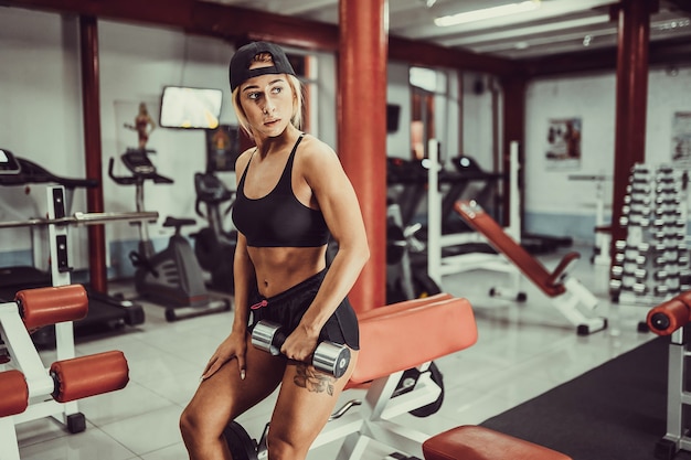 Fit exercice de fille avec des haltères dans la salle de gym.