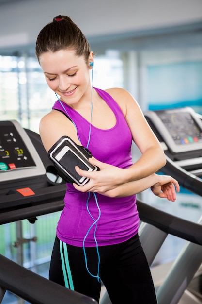 Fit femme à l&#39;aide de smartphone sur tapis roulant à la gym