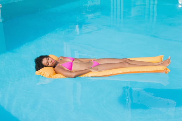 Fit femme allongée sur lilo dans la piscine