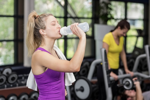 Fit femme buvant à la bouteille d&#39;eau à la gym