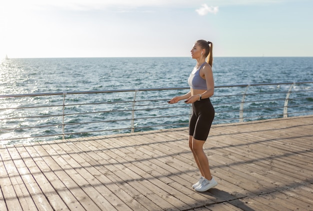 Fit femme corde à sauter sur la plage au lever du soleil