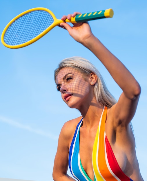 Fit femme avec un corps sexy en maillot de bain rayé jouer au tennis avec une raquette de tennis