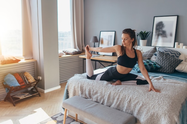 Fit femme faisant de l'exercice sur le lit à la maison.