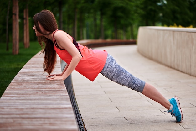 Fit femme faisant de l'exercice de planche en plein air dans le parc