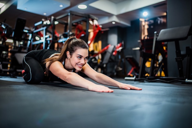 Fit femme faisant des exercices d&#39;étirement sur le sol du gymnase.