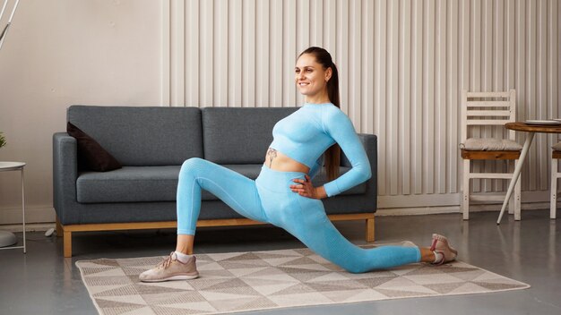 Fit femme faisant des exercices de fente avant une jambe avant à la maison.