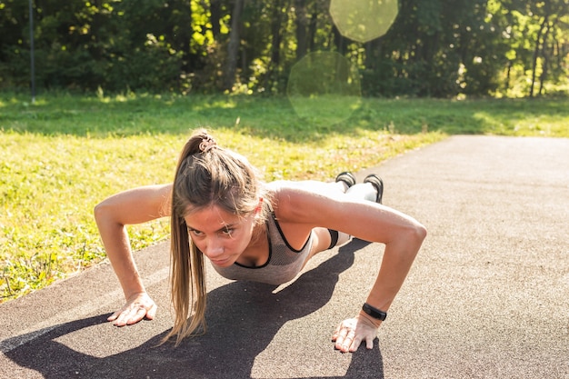 Fit femme faisant des pompes dans le parc.