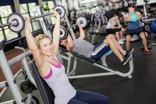 Fit femme soulevant des haltères dans un gymnase de crossfit