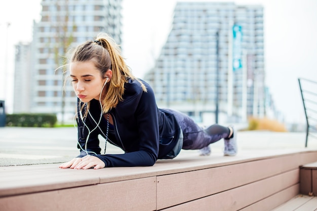 Fit fille faisant de l'exercice de planche en plein air dans le parc