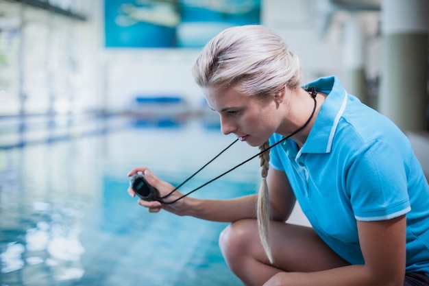 Fit formateur montrant chronomètre à la piscine