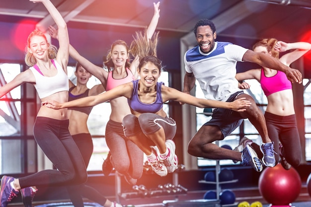 Photo fit groupe souriant et sautant dans la salle de gym