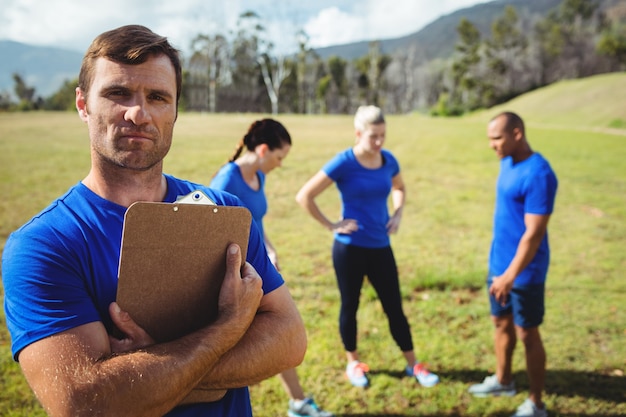 Fit homme debout et tenant un presse-papiers dans le camp d'entraînement