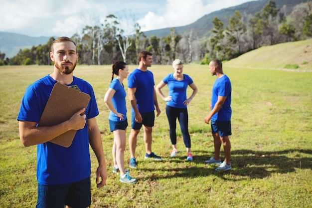 Fit homme debout et tenant un presse-papiers dans le camp d'entraînement