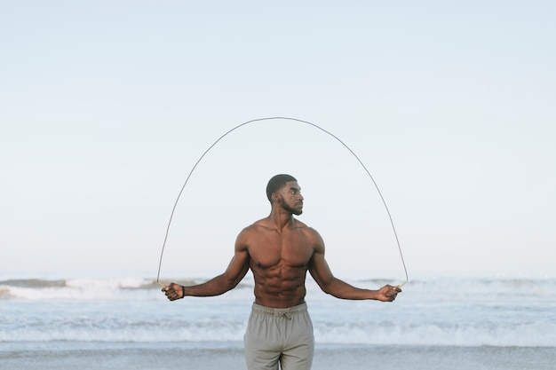 Fit homme saut à la corde à la plage