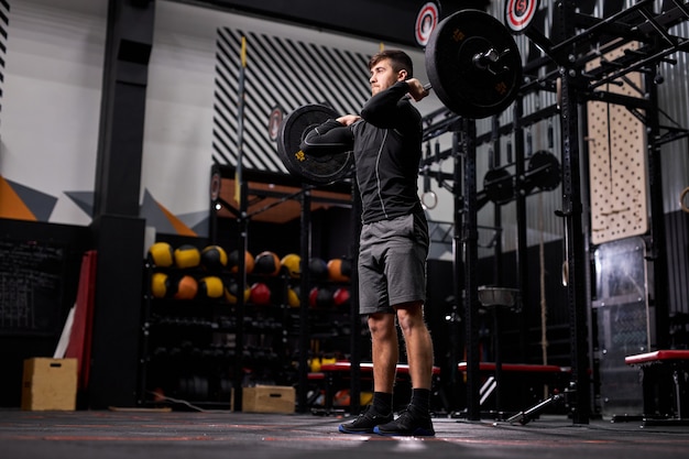 Fit homme soulevant des haltères dans la salle de sport crossfit, le concept de musculation et d'haltérophilie. homme en tenue de sport engagé dans un entraînement cross fit, entraînement seul