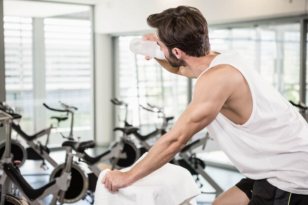 Fit homme sur un vélo d&#39;exercice de l&#39;eau potable à la gym