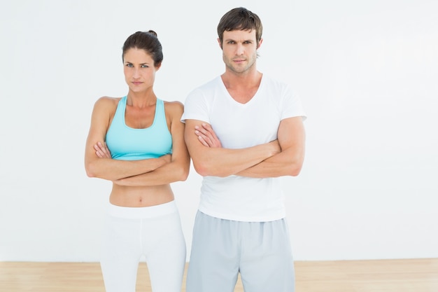 Fit jeune couple avec les bras croisés dans le studio de remise en forme