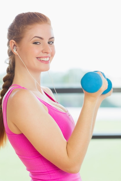 Fit la jeune femme exerçant avec haltères dans le studio de remise en forme