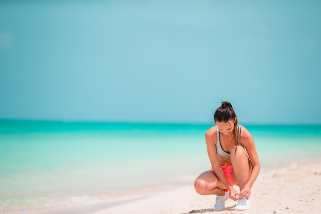 Fit la jeune femme sur la plage tropicale en tenue de sport