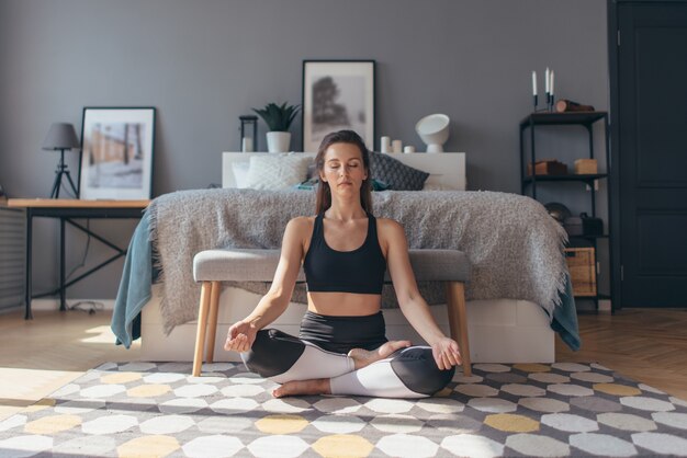 Fit jeune femme travaillant à la maison, faisant des exercices de yoga, elle se détend et se calme.