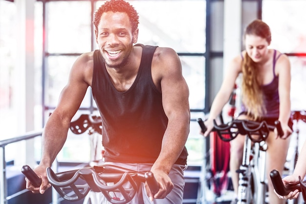 Fit man working out at spinning class in gym