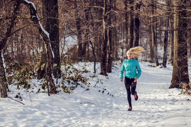 Fit sportive jogging sur chemin enneigé en forêt en hiver. Mode de vie sain, forme d'hiver