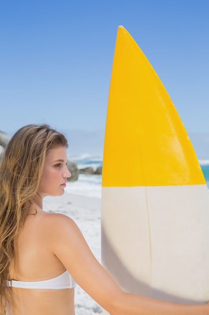 Fit surfeur fille tenant sa planche de surf sur la plage