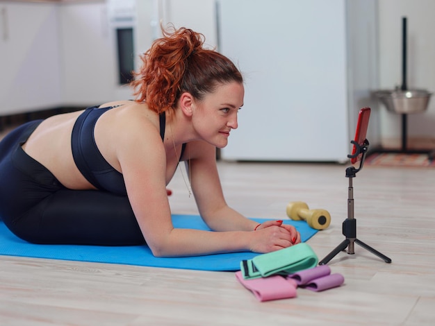 Fit Young Woman Excersising At Home Regarder un didacticiel vidéo sur smartphone