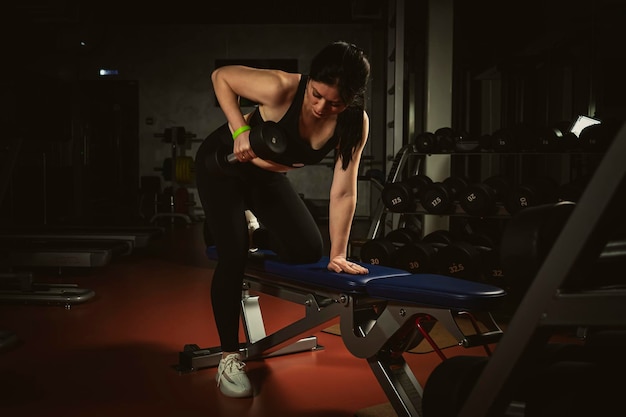 Fit young woman lifting weight in gym fille sportive sur pied exerçant dans un centre de remise en forme avec muet