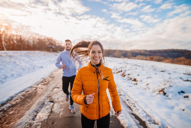 Fitness couple hiver matin exercice à la montagne enneigée.