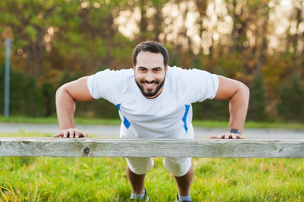 Fitness dans le parc. Jeune et sportif homme s&#39;entraînant en plein air dans le sportswear. Sport, santé, athlétisme.