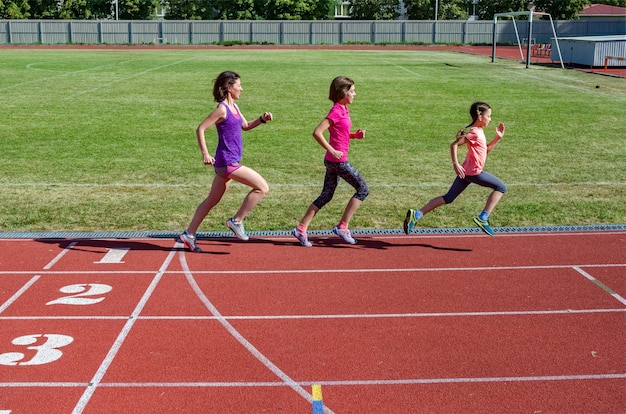 Fitness Familial, Mère Et Enfants En Cours D'exécution Sur La Piste Du Stade, Exercice Avec Enfants Et Sport Concept De Mode De Vie Sain