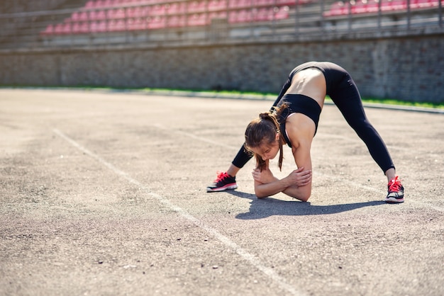 Fitness femme faisant des étirements sur le sadium avant l'entraînement