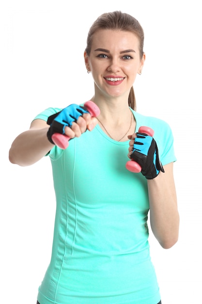 Fitness femme en gants et haltères sur un mur blanc