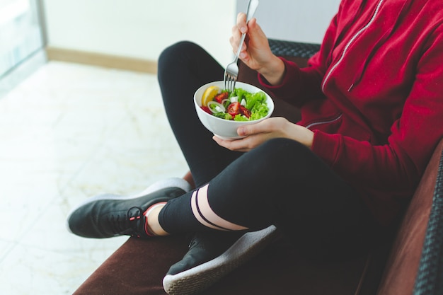 Fitness femme se repose et mange une salade fraîche et saine après une séance d'entraînement. Concept de remise en forme et de mode de vie sain.